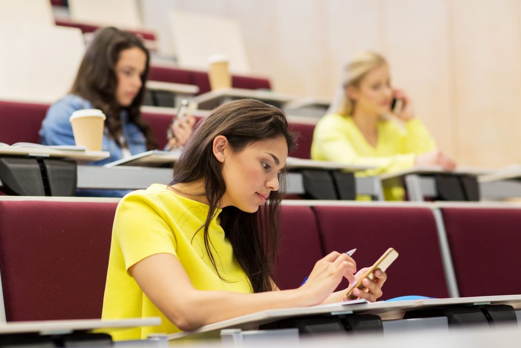 Female students with smartphones on lecture.