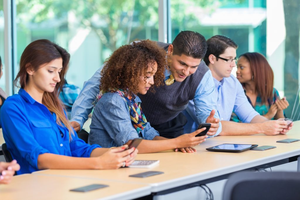 Professor reading note on student's smart phone in classroom.