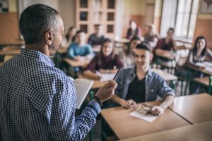 Teacher in classroom talking to undergraduate students.