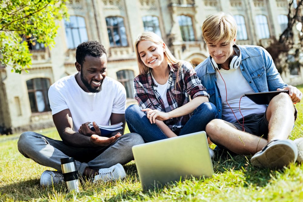 students smiling and pointing at a laptop