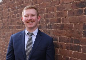 A photo of Hunter. He has short hair, a moustache and is wearing a suit and tie.
